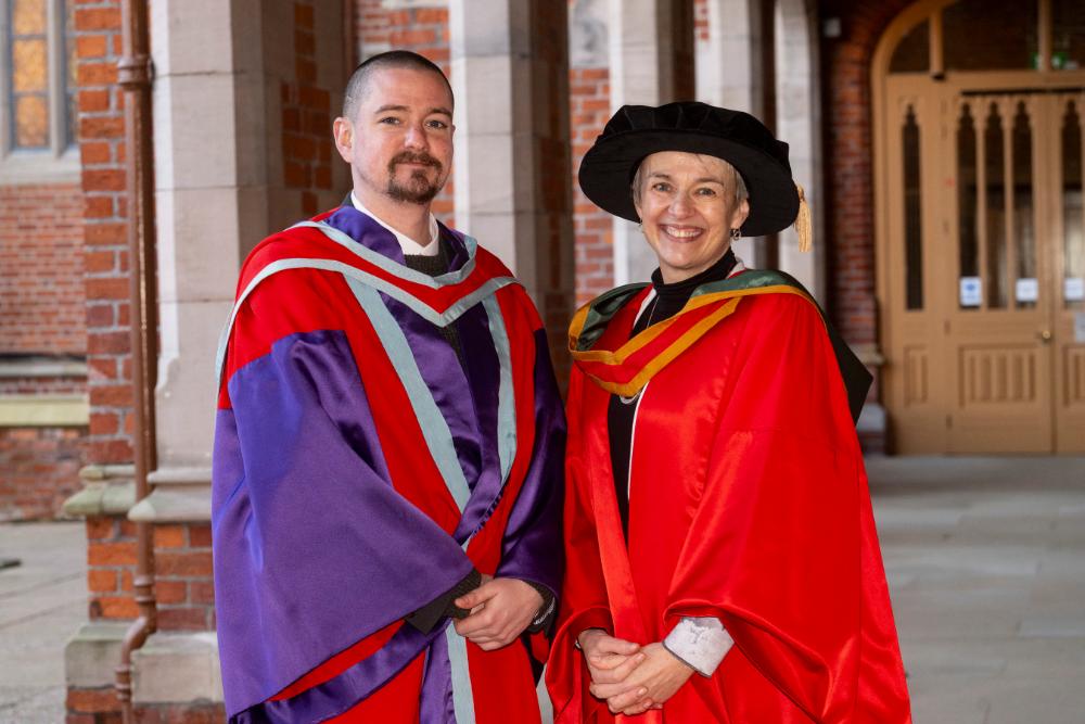 Two graduates standing together smiling and celebrating their success.